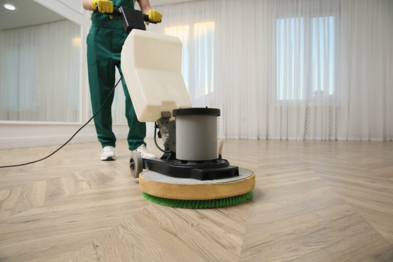 Professional janitor cleaning parquet floor with polishing machine indoors, closeup